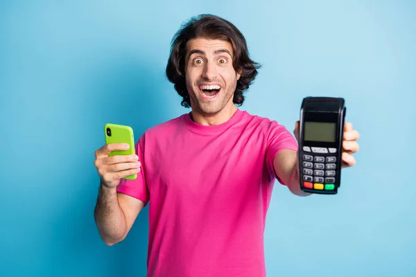 Retrato de bom cara alegre surpreso segurando em mãos gadget pos terminal aplicativo de compra cibernética isolado sobre fundo de cor azul brilhante — Fotografia de Stock