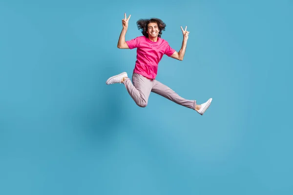 Longitud completa tamaño del cuerpo vista de chico alegre atractivo saltando corriendo mostrando v-signo aislado sobre fondo de color azul brillante —  Fotos de Stock