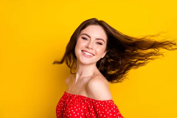Foto retrato de chica feliz con el pelo ondulado en camisa roja girando con el pelo volador sonriendo aislado color amarillo brillante fondo —  Fotos de Stock