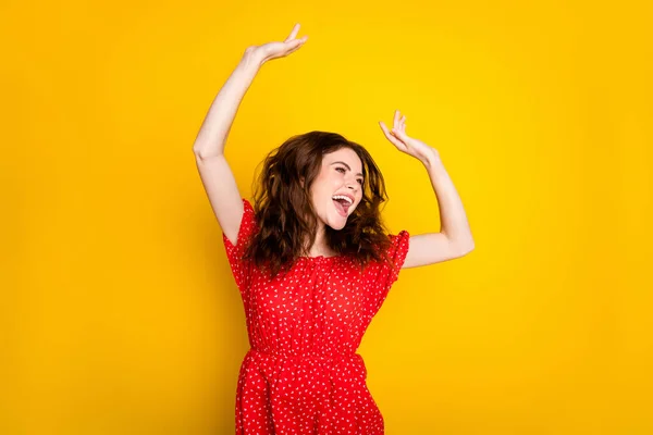 Foto retrato de chica feliz con el pelo ondulado en vestido rojo riendo bailando en la fiesta buscando copyspace aislado color amarillo vivo fondo — Foto de Stock