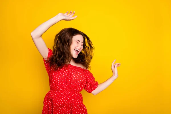 Kırmızı elbiseli, dalgalı saçlı mutlu bir kızın fotoğrafı izole edilmiş sarı arka planda dans ederken gülüyor. — Stok fotoğraf