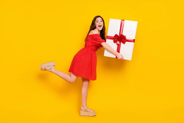 Volledige lengte profiel foto van opgewonden vrolijke persoon handen houden zware grote giftbox geïsoleerd op gele kleur achtergrond — Stockfoto