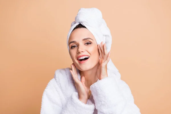Porträt von charmanten fröhlichen verträumten Mädchen tragen Bademantel berühren weiches Gesicht isoliert über beige Pastellfarbe Hintergrund — Stockfoto