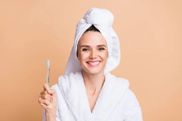 Retrato de menina saudável muito alegre usar roupão de banho segurando na mão nova escova de dentes isolado sobre fundo cor pastel bege — Fotografia de Stock