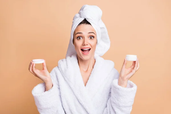 Foto de mulher encantadora feliz surpresa segurar creme tratamento chocado isolado no fundo cor bege — Fotografia de Stock