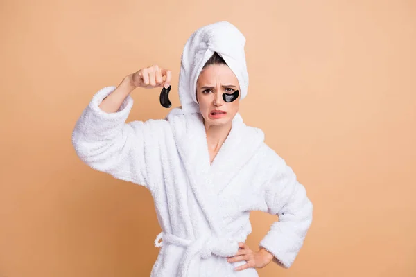 Retrato de menina muito dissafisfied usar roupão de banho desagradável nutrir manchas oculares isoladas sobre fundo cor pastel bege — Fotografia de Stock