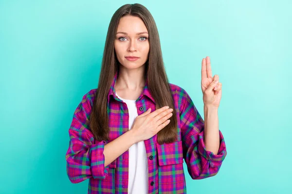 Retrato de chica seria atractiva tocando el corazón diciendo juramento mostrando dos dedos aislados sobre fondo de color verde azulado brillante —  Fotos de Stock