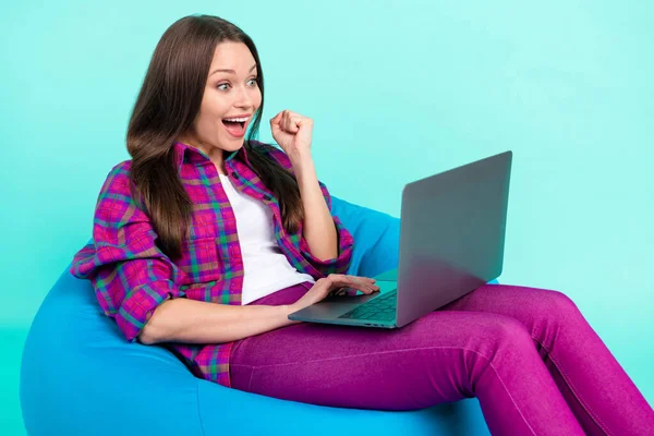 Portret atrakcyjnej szczęśliwej dziewczyny siedzi w torbie krzesło za pomocą laptopa o zabawy odizolowane na jasnym tle ciemny morski kolor — Zdjęcie stockowe