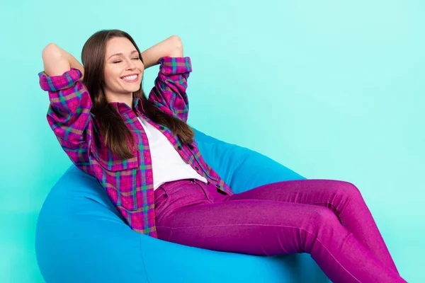 Πορτρέτο της ελκυστική ονειρική χαρούμενο κορίτσι που βρίσκεται στην καρέκλα τσάντα ύπνου απομονωμένη πάνω από φωτεινό φόντο teal χρώμα — Φωτογραφία Αρχείου