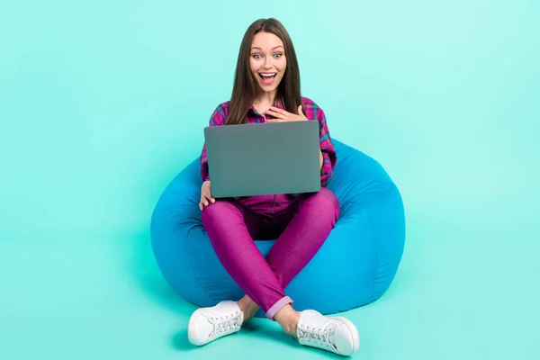 밝은 청록색 배경에 고립된 재미있는 영화를 노트북으로 보면서 의자에 앉아 있는 매력적 인 명랑 한 소녀의 모습 — 스톡 사진