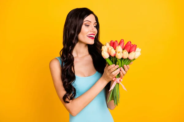 Foto de señora positiva mantenga tulipanes ramo tierna cara desgaste azul singlet aislado color amarillo fondo — Foto de Stock