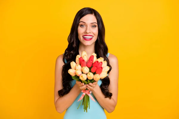 Foto de alegre dama mantenga ramo flores mirada cámara desgaste azul superior aislado color amarillo fondo — Foto de Stock