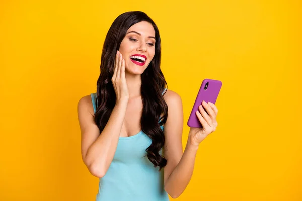 Foto de senhora linda segurar telefone palma bochecha olhar tela desgaste azul singlet isolado cor amarela fundo — Fotografia de Stock