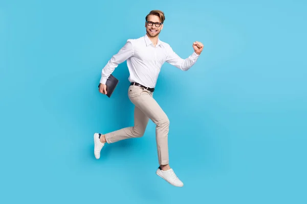 Full body profile side photo of cheerful young happy man go empty space hold laptop isolated on blue color background