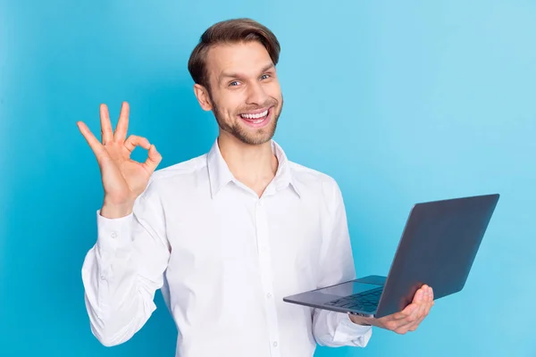 Zdjęcie wesoły młody pozytywny człowiek trzymać dobrze znak laptop programista izolowany na tle niebieskiego koloru — Zdjęcie stockowe
