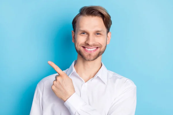 Фото веселого молодого человека указывать пальцем пустое пространство хорошее настроение объявление изолированы на синем фоне цвета — стоковое фото