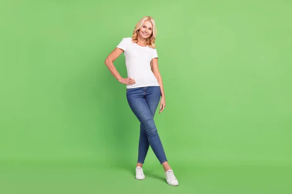 Longitud completa cuerpo tamaño foto senior mujer vistiendo blanco camiseta jeans sonriendo aislado en pastel verde color fondo — Foto de Stock