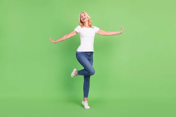 Full body foto van zoete blonde senior dame dans dragen witte t-shirt jeans geïsoleerd op groene kleur achtergrond — Stockfoto