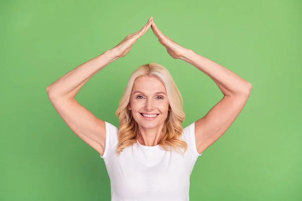 Fénykép az optimista szőke idősebb hölgy karok tető viselni fehér póló elszigetelt pasztell zöld színű háttér — Stock Fotó