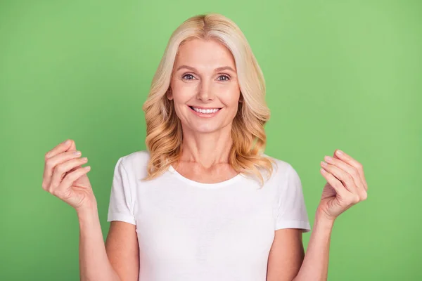 Foto retrato mulher mais velha sorrindo pedindo dinheiro em t-shirt branca isolada no fundo cor verde pastel — Fotografia de Stock