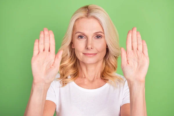 Zdjęcie słodkie blondynka starsza pani pokazać znak stopu nosić biały t-shirt izolowane na pastelowy zielony kolor tła — Zdjęcie stockowe