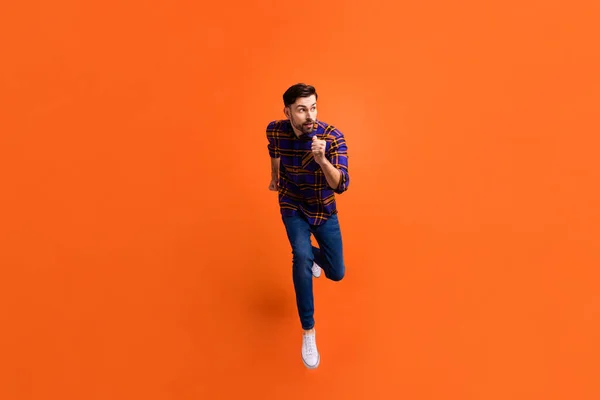 Full body portret van zorgeloze knappe man kijken geïnteresseerd lege ruimte geïsoleerd op oranje kleur achtergrond — Stockfoto