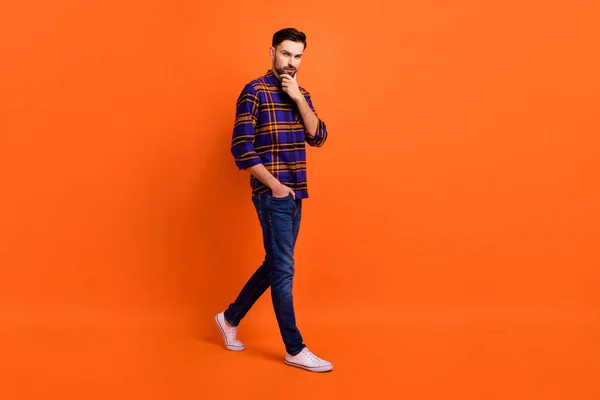 Retrato de perfil de tamaño completo de la mano de la persona positiva en la barbilla caminando mirada cámara aislada en fondo de color naranja — Foto de Stock