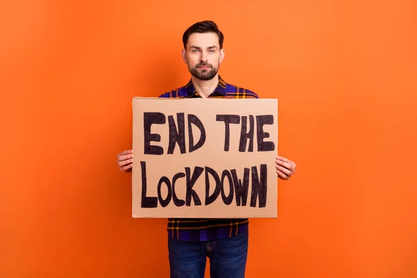 Photo of youn concentrated man arms hold paper end the lockdown poster isolated on orange color background — Stock Photo, Image