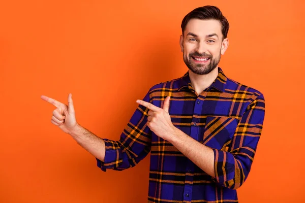 Photo de jeune homme heureux sourire positif indiquer doigts espace vide ad select recommander isolé sur fond de couleur orange — Photo