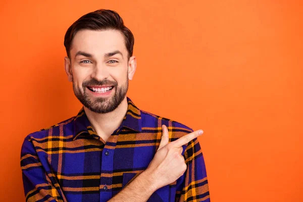 Fénykép a fiatal vidám férfi boldog mosoly jelzi ujj üres tér hirdetés promóciós tanácsot elszigetelt felett narancs színű háttér — Stock Fotó