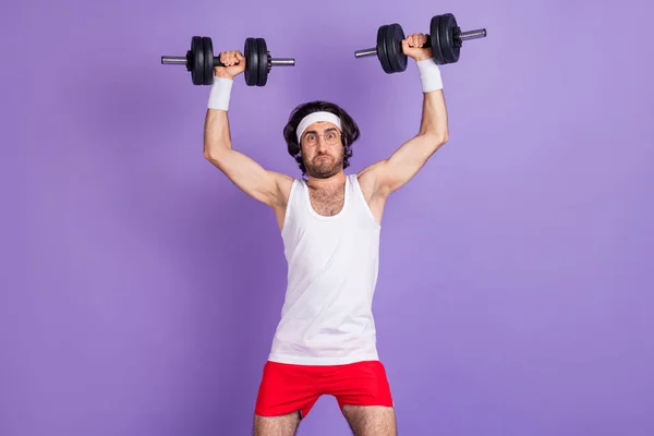 Foto von Kerl heben Hände halten schwere Hanteln Mühe tragen Sportbekleidung Brille isoliert violetten Hintergrund — Stockfoto