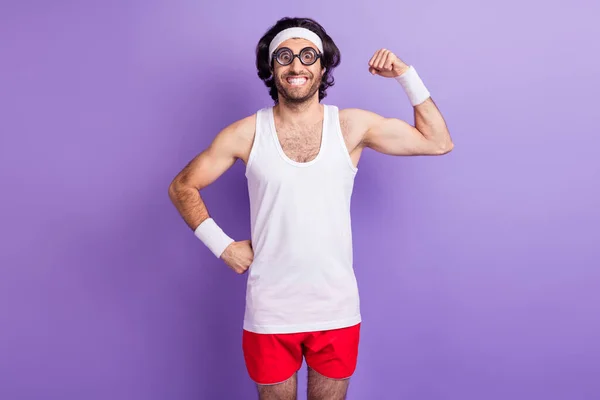 Photo of happy funky positive young man hold hands show muscles wear glasses isolated on purple color background — Stock Photo, Image