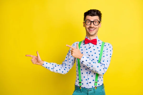 Foto de hombre joven feliz sonrisa positiva indican dedos espacio vacío anuncio promo recomendar aislado sobre fondo de color amarillo —  Fotos de Stock