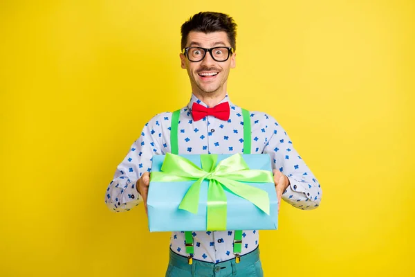 Φωτογραφία του νεαρού όμορφος άντρας ευτυχής θετικό χαμόγελο δώσει κουτί δώρου πάρτι γενεθλίων απομονωμένο πάνω από κίτρινο χρώμα φόντο — Φωτογραφία Αρχείου