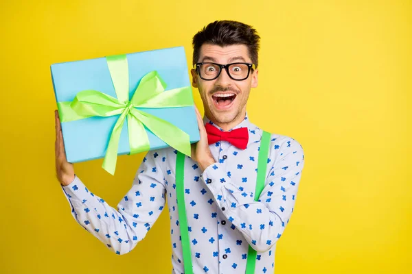 Retrato de cara alegre atraente vestindo camisa de impressão segurando em mãos giftbox isolado sobre fundo de cor amarelo brilhante — Fotografia de Stock