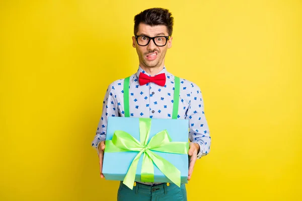 Retrato de tipo divertido atractivo sosteniendo en las manos giftbox mueca disgusto aislado sobre fondo de color amarillo brillante —  Fotos de Stock