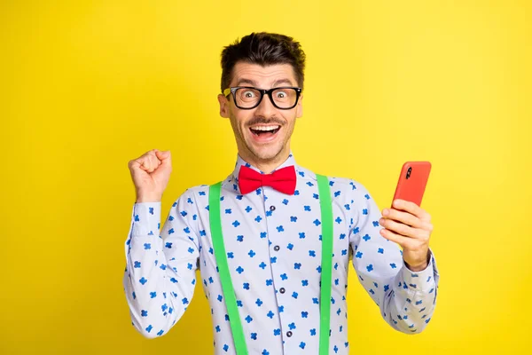 若い興奮した男の写真幸せなお祝い勝利使用携帯電話拳手孤立以上黄色の色の背景 — ストック写真