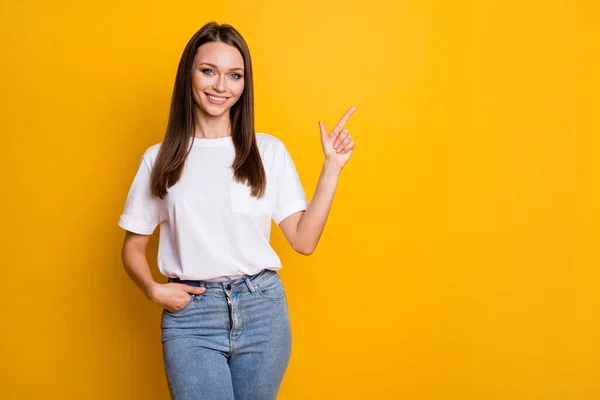 Foto portret van vrouw wijzend vinger naar lege ruimte een hand in zak geïsoleerd op levendige geel gekleurde achtergrond — Stockfoto