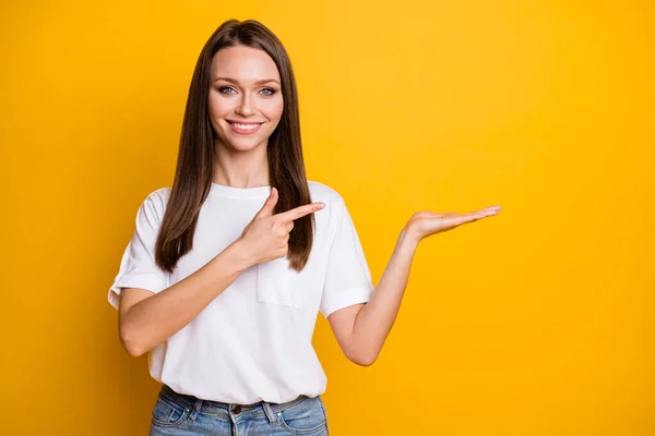 Fotoporträt einer Frau, die eine Leerstelle in der Hand hält und mit dem Finger darauf zeigt, isoliert auf leuchtend gelbem Hintergrund — Stockfoto