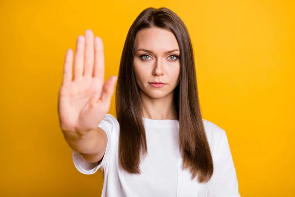 Foto portret van ernstige meisje tonen stopsignaal met wazig palm geïsoleerd op levendige gele kleur achtergrond — Stockfoto