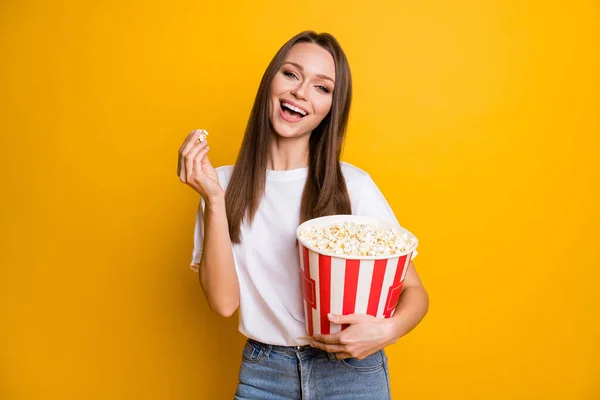 Photo portrait of happy girl with brunette hair keeping carton box with pop corn laughing isolated vibrant yellow color background — Stock Photo, Image