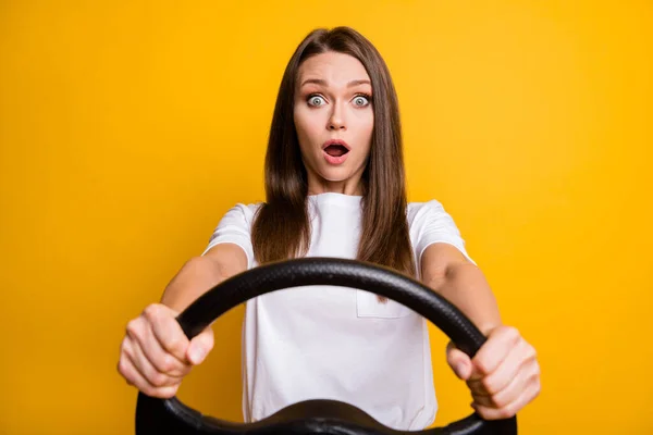 Foto retrato de miedo chica morena sosteniendo volante conducción primera vez aislado vívido color amarillo fondo —  Fotos de Stock