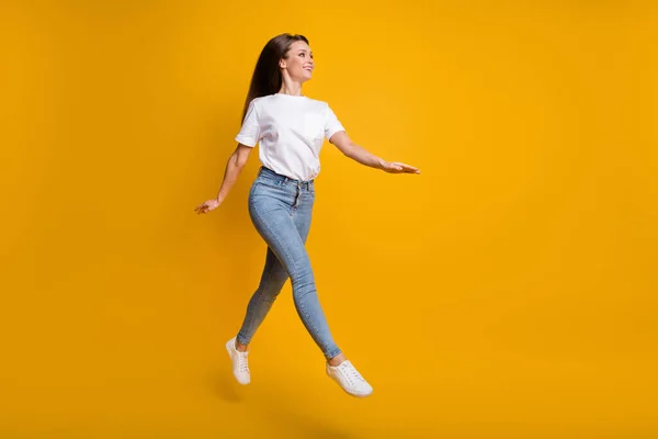 Longitud completa tamaño del cuerpo foto de la niña saltando caminando mirando el espacio vacío aislado en el fondo de color amarillo brillante — Foto de Stock