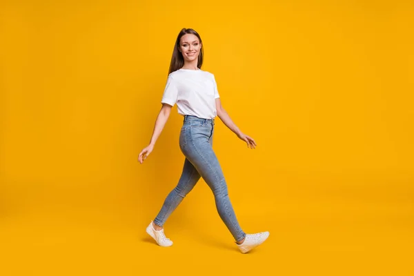 Longitud completa tamaño del cuerpo foto de la niña dando un paso adelante mirando copyspace sonriendo aislado sobre fondo de color amarillo brillante —  Fotos de Stock