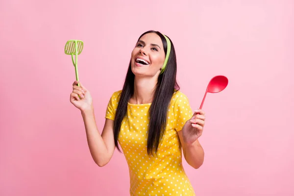 Φωτογραφία από αστεία ευτυχισμένη νεαρή νοικοκυρά κατέχουν μαγειρικά σκεύη φορούν διάστικτη t-shirt που απομονώνονται σε λάμψη παστέλ ροζ χρώμα φόντο — Φωτογραφία Αρχείου