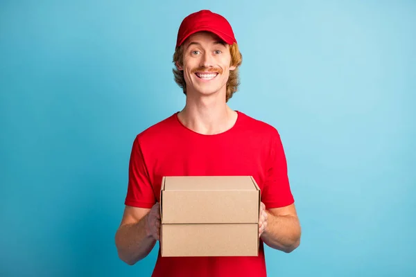 Foto von positiver gutaussehender Person Arme halten Boxen zahmes Lächeln suchen Kamera isoliert auf blauem Hintergrund — Stockfoto