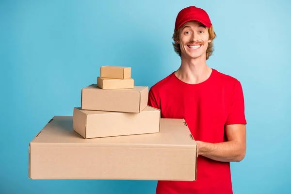 Foto de amigável jovem trabalhador mãos segurar diferentes caixas de tamanho isolado no fundo de cor azul — Fotografia de Stock