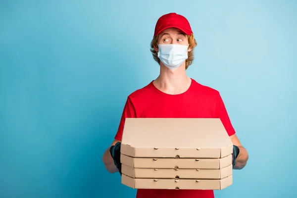Fénykép a fiatal srác tartsa karton pizza dobozok megjelenés üres tér kopás arc széf maszk elszigetelt kék színű háttér — Stock Fotó