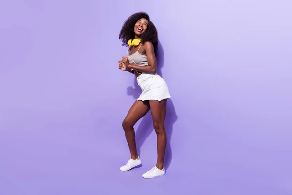 Pleine longueur profil photo de côté de jeune afro fille sourire heureux ont des écouteurs de danse amusant isolé sur fond de couleur pourpre — Photo