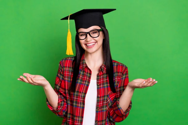 Foto di bruna indifesa giovane donna spalle scrollate indossando occhiali cappello graduazione camicia rossa isolata su sfondo di colore verde — Foto Stock